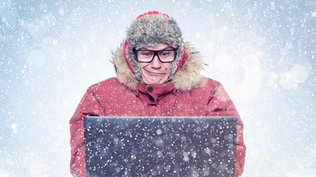 Man in glasses and red winter clothes with laptop, cold, snow.