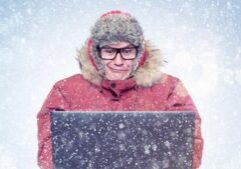 Man in glasses and red winter clothes with laptop, cold, snow.